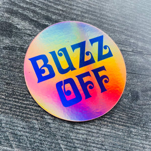 3” round holographic sticker with “BUZZ OFF” written in electric blue vintage font 