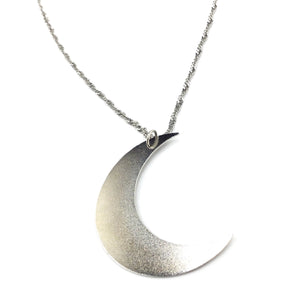 26” shiny silver metal fancy link style necklace with a large silver metal crescent moon pendant. Shown in close up