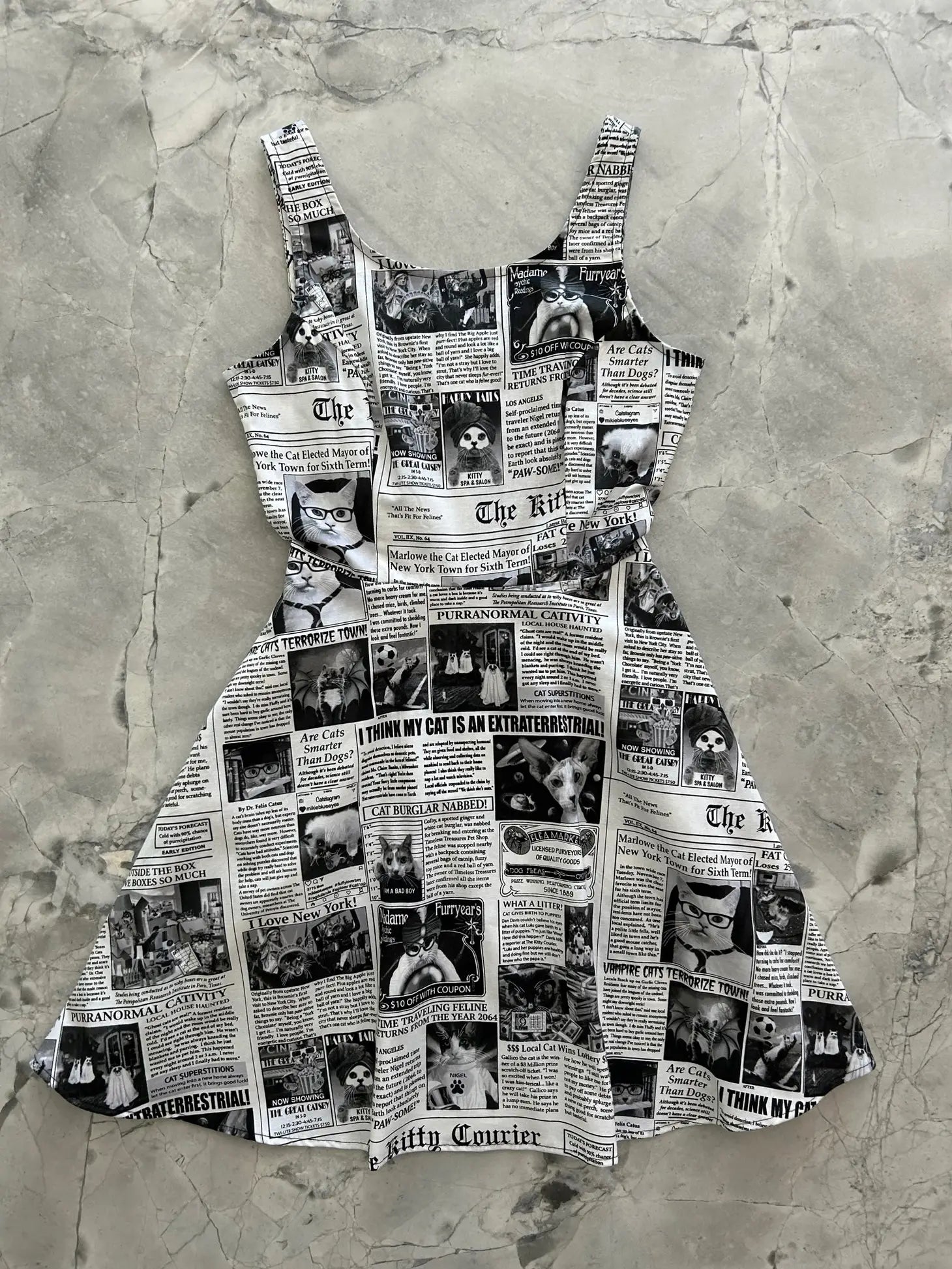 Cotton sleeveless skater style minidress with princess seaming and scoop neck. It has an all over black and white newspaper pattern themed to cats