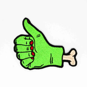 Embroidered patch of a bright green severed hand with visible bone and red fingernails giving a thumbs up