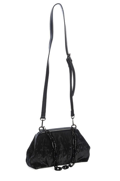 Black velvet purse with embossed damask pattern of chandeliers, candles, crescent moons, and roses. Has a black plastic chain link shoulder strap and faux leather hinge detail on the exterior. Shown from the side with faux leather crossbody strap attached