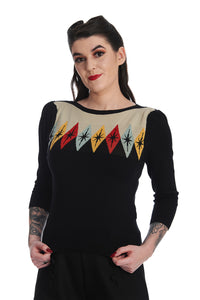Black boatneck sweater with 3/4 sleeves and a blue, red, yellow diamond pattern across the chest on a beige background with black starbursts. Shown from the front