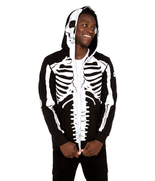Male model wearing a black fleece lined hooded sweatshirt with an all-over anatomical skeleton screen printed design. Shown unzipped from the front