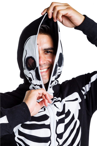 A male model wearing a black lightweight fleece zip-up jumpsuit with an all-over anatomical skeleton screen printed motif. The zipper runs to the top of the hood and it has two mesh covered eye holes. Seen up close with hood being zipped up and held with one hand