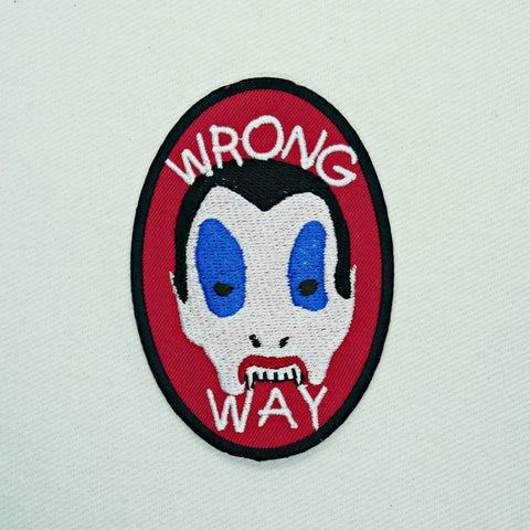 Oval shaped red cotton twill embroidered patch with a black border. Features image of the Vampire Kid from the movie Trick ‘r Treat with the message “wrong way” in large white capital letters