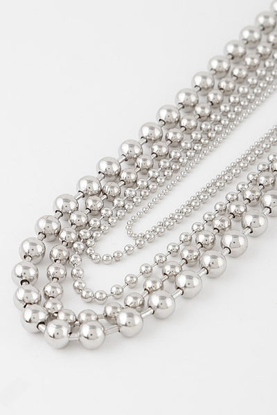 Five strand long necklace made of rounded shiny silver metal beads with a toggle closure. Shown in close up
