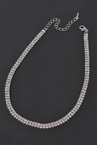 Double row of rhinestones set in silver metal forming a choker necklace with lobster clasp and 5” extender. Seen flat