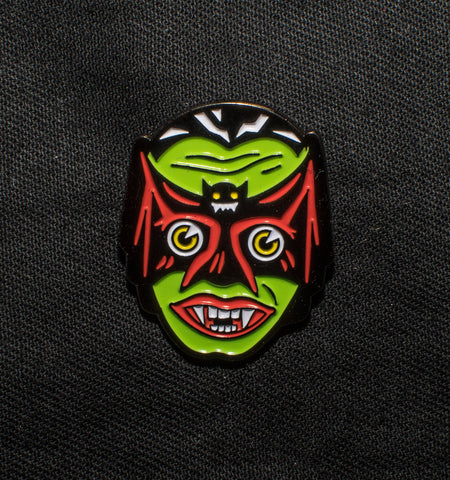 Gunmetal enamel pin with neon pink and green detail of a vampire wearing a bat shaped mask