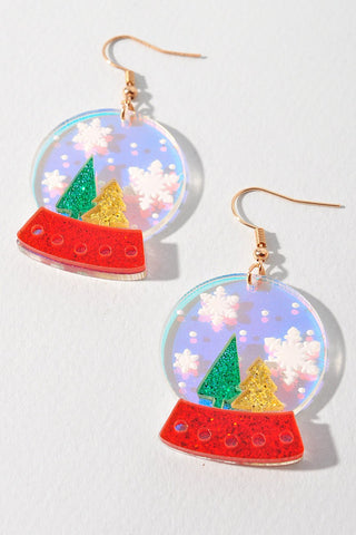 A pair of acrylic snow globe earrings with white snowflakes on the flash finished “globe” and glittery green and red trees