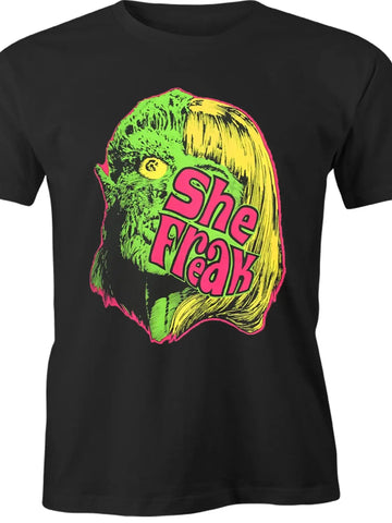 Black unisex t shirt with neon green, yellow, pink print of a green skinned melting woman with blonde hair and “She Freak” written in pink across her face