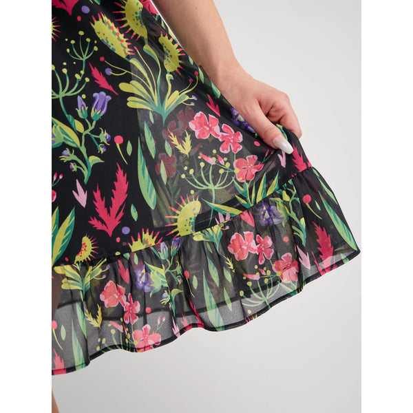 Model wearing a mini dress with a botanical pattern including Venus Flytraps on a black background. It has a square neckline, slightly puffed short sleeves, and a full skirt with a ruffled hem. Shown in close up to display pattern detail