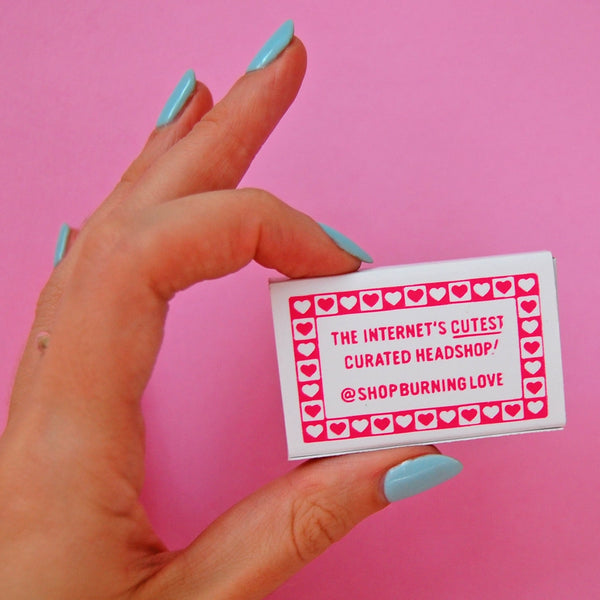 Back of box of matches with message “THE INTERNET’S CUTEST CURATED HEADSHOP!” printed in bright pink with a checkered heart border