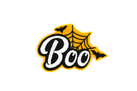 Orange felt patch with “Boo” written in white cursive with black background and black spiderweb with two black bats in the background 