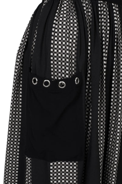 midi length skirt in a black and grey check plaid with alternating black vertical stripes. It has a self waistband with silver metal D-ring detail at the left hip and large black patch pockets with silver metal grommets at the hem of the pockets. Shown in close up of pocket detail 