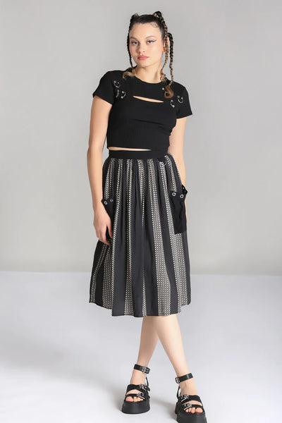 A model wearing a midi length skirt in a black and grey check plaid with alternating black vertical stripes. It has a self waistband with silver metal D-ring detail at the left hip and large black patch pockets with silver metal grommets at the hem of the pockets. Shown from the front