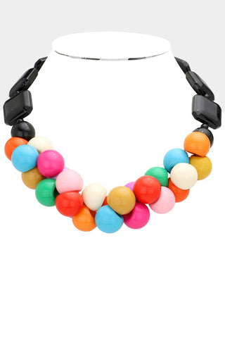 Resin beaded necklace made of multicolored shiny round beads clustered at the front of the necklace surrounded by square and round black beads