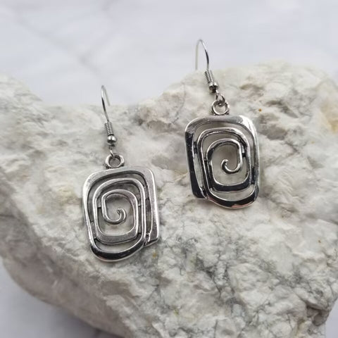 A pair of dangle earrings with silver metal square spiral charms 