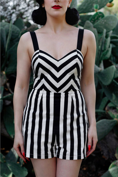A model wearing a playsuit made of stretch black and white cotton. The playsuit has a sweetheart neckline, princess seaming, and wide black adjustable straps. Shown from the front in close up