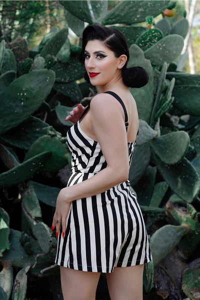 A model wearing a playsuit made of stretch black and white cotton. The playsuit has a sweetheart neckline, princess seaming, and wide black adjustable straps. Shown from the back