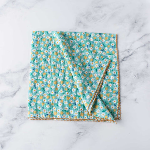 Square cotton scarf in a ditsy yellow and white flower print with green and blue leaves on a minty blue green background. Scarf has a deep yellow embroidered scalloped trim