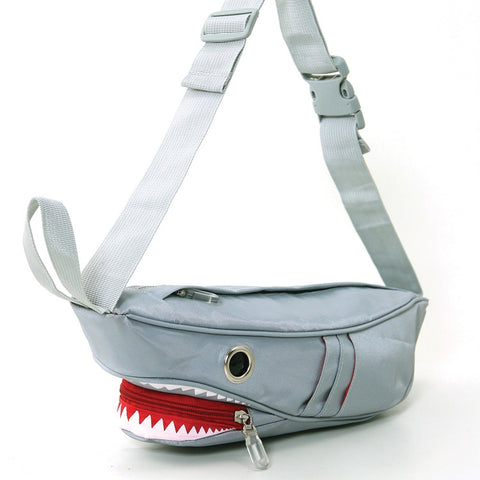 Novelty fanny pack shaped like a shark in grey nylon with large silver grommets for eyes. It has 6 exterior pockets for gills and zippered access to the interior through the shark’s mouth. Matching grey nylon adjustable strap. Shown flat from the side