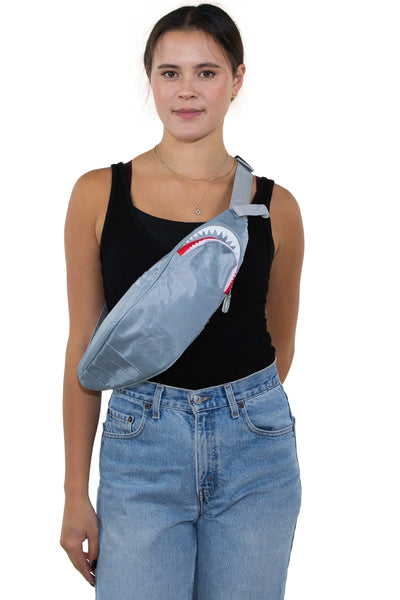 Novelty fanny pack shaped like a shark in grey nylon with large silver grommets for eyes. It has 6 exterior pockets for gills and zippered access to the interior through the shark’s mouth. Matching grey nylon adjustable strap. Shown worn by a model on their chest