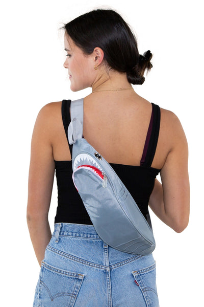 Novelty fanny pack shaped like a shark in grey nylon with large silver grommets for eyes. It has 6 exterior pockets for gills and zippered access to the interior through the shark’s mouth. Matching grey nylon adjustable strap. Shown worn by a model on their back