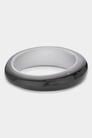 Asymmetrical shiny black resin bangle with a pearly finish and clear top and bottom. Shown to display asymmetrical shape