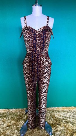 A sleeveless catsuit in a brown leopard print with a sweetheart neckline and exaggerated cuffs at the bodice and hip pockets. Shown on a dress form from the front