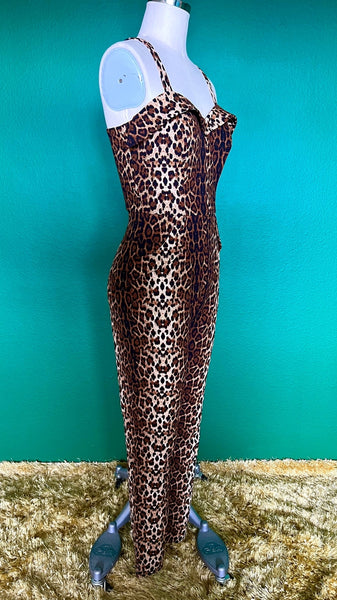 A sleeveless catsuit in a brown leopard print with a sweetheart neckline and exaggerated cuffs at the bodice and hip pockets. Shown on a dress form from the side