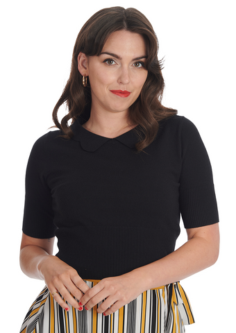 A model wearing a knit black sweater with elbow length sleeves, a scalloped collar, and wide ribbed bottom band. Shown from the front 