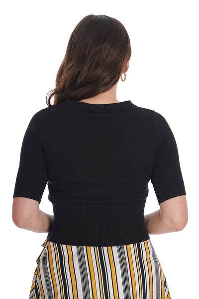 A model wearing a knit black sweater with elbow length sleeves, a scalloped collar, and wide ribbed bottom band. Shown from the back 