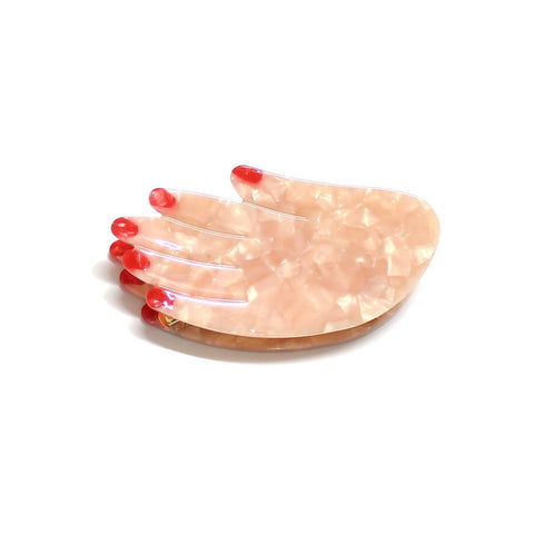Acetate hair claw clip in the shape of a hand with beige skin and red fignernails