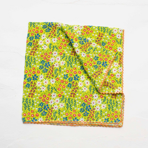 Cotton seersucker lime green square scarf with all over wildflower pattern in white, red, green, and blue. Has an orange embroidered scalloped trim