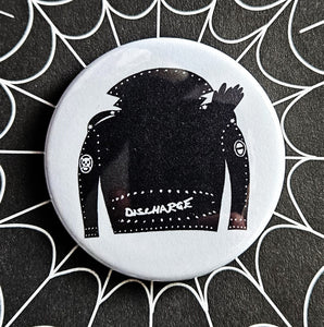 1.25” round pinback button with black and white illustration of leather jacket with Discharge logo printed on bottom panel of jacket