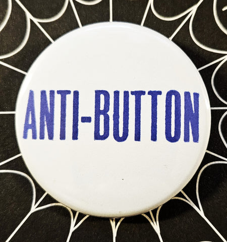 1.25” round button with white background and “ANTI-BUTTON” written in blue 