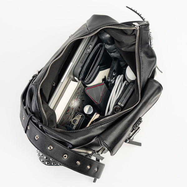 black textured faux leather crossbody bag with 8 exterior pockets with silver metal zip closure and cone stud & o-ring detail on oversized strap detail. Bag has 27" adjustable self strap. Shown open from top to display interior pockets