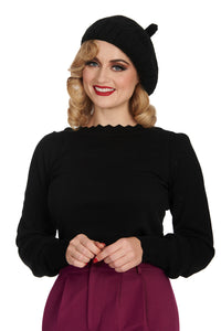 Model wearing long sleeved black knit sweater with scalloped slash neckline, slightly puffed shoulders, geometric pointelle details at the sleeves, and scalloped cuffs and bottom band. Shown from the front