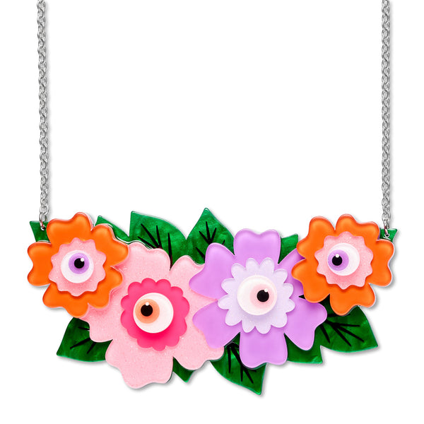 A colorful floral necklace with four stylized flowers in orange, pink, and purple, all with eyeball centers, and accented with green leaves and a silver chain.