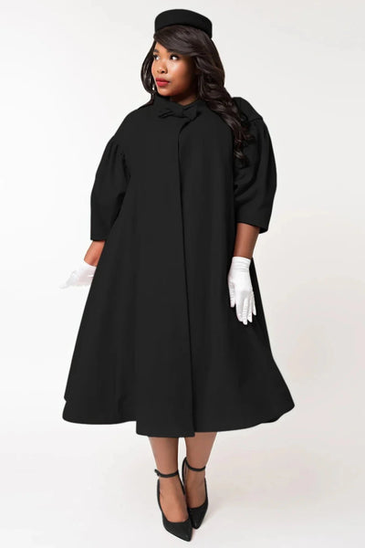  1960s style black swing coat with bow detail at the neck, and puffed 1/2 sleeves, worn by a model