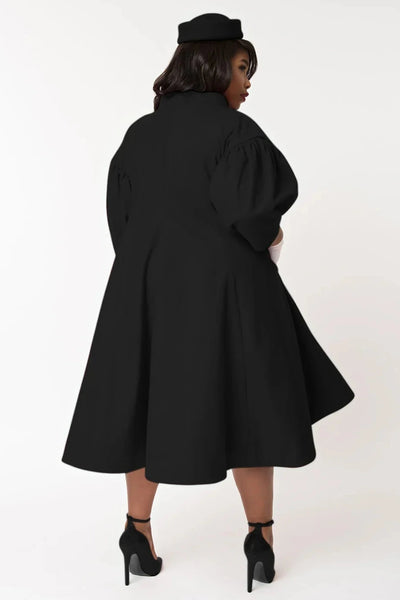  1960s style black swing coat with bow detail at the neck, and puffed 1/2 sleeves, shown back view worn by a model