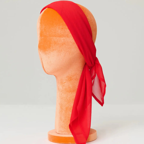 Red chiffon headscarf on a mannequin head against a plain background
