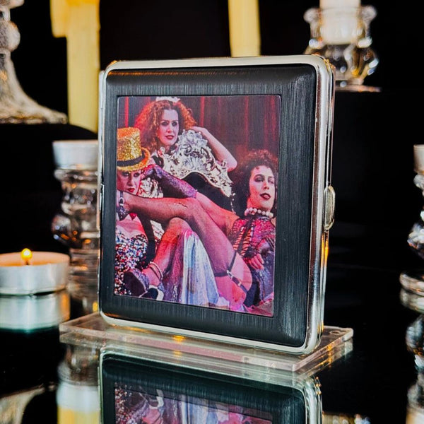 square metal cigarette case with lenticular image of Columbia, Magenta, and Frank N. Furter from the Rocky Horror Picture Show on front of case. Shown closed