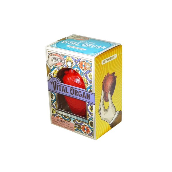 Red rubber squeeze toy in the shape of an anatomical heart shown in cardboard packaging from side