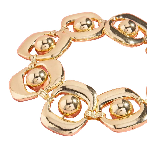 gold metal chain belt made of linked flat oblong discs with a round bead in its middle with chain extender. Shown flat in close up