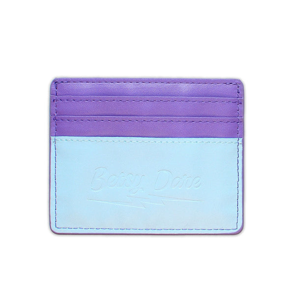 rectangular faux leather 6 slot card holder in bright purple and light blue with diagonal teal faux leather lightning bolt applique in middle. Shown from back with solid purple and blue side and subtle branded stamping