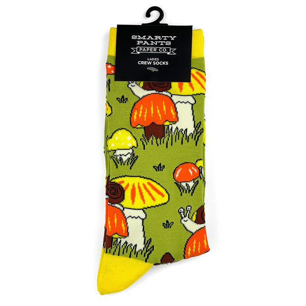 Pair of socks with orange and yellow mushrooms with snails design on a green background. Shown flat In packaging 