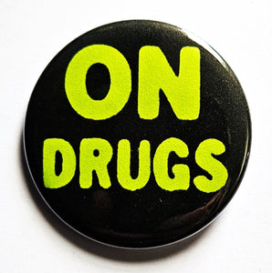 1.25" round pinback button with black background and "ON DRUGS" written in neon green