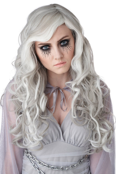 A woman wearing a long, wavy platinum white wig with dramatic dark eye makeup and a pale gray costume against a plain white background. Shown from the front