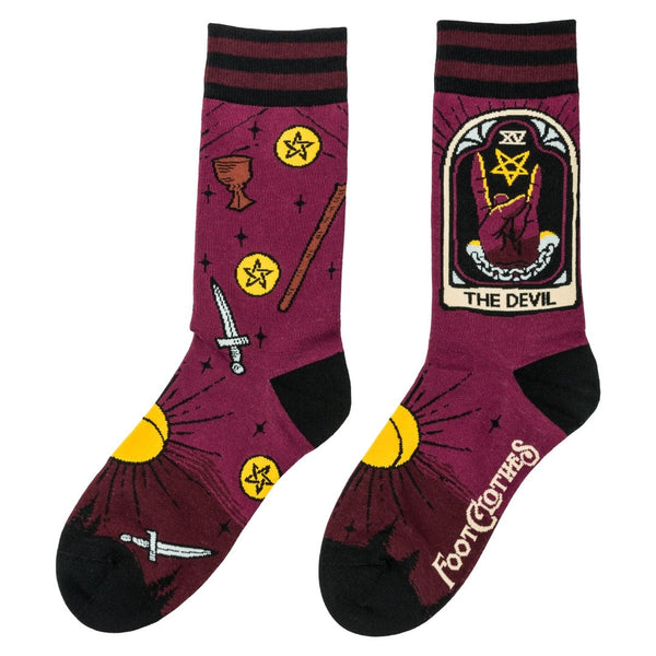 Unisex cotton blend crew socks with striped burgundy and black cuffs and black toes & heels. Each outer ankle has Devil tarot imagery with a hand giving devil fingers alongside a pentagram. Socks have all over pattern of suns, chalices, swords, wands, and pentacles. Shown flat